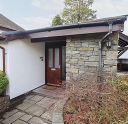 An entrance with a stone wall and wooden door at Mardale in Ambleside