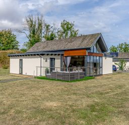 A modern house with a patio and outdoor seating on a grassy lawn at Wood Sage in Bamburgh