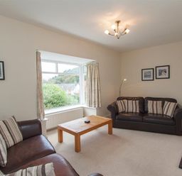 A living room with two brown leather sofas striped cushions wooden coffee table and a large window at The Haven in Keswick