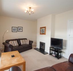 A living room with two leather sofas a wooden coffee table a television on a stand a fireplace and framed pictures on the wall at The Haven in Keswick