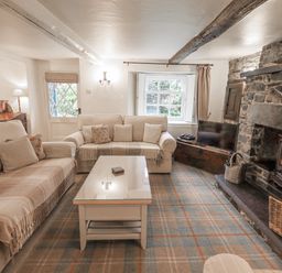 A living room with two sofas a coffee table a fireplace and a television at Syke Cottage in Hawkshead