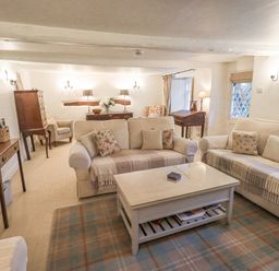 A living room with two sofas a coffee table armchairs wooden furniture and lamps at Syke Cottage in Hawkshead