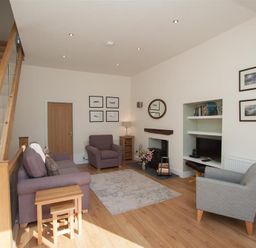A living room with two armchairs a sofa a rug and a staircase at Mylnbeck in Bowness