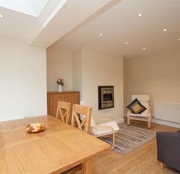 A dining area with a wooden table and chairs and a seating area with armchairs and a sofa at Fell End in Keswick