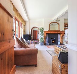 A living room with a sofa a fireplace and wooden furniture at The Stables in Ambleside