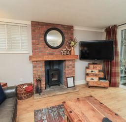 A living room with a fireplace and television at Chapel Hill Cottage in Ambleside