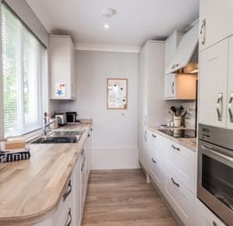 A kitchen with wooden countertops white cabinets a built in oven and a window with blinds at Fairview in Bowness