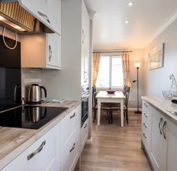 A kitchen with a stovetop kettle dining table and chairs near a window at Fairview in Bowness