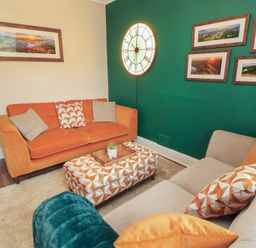 A living room with sofa and ottoman at Gildabrook Cottage in Bowness