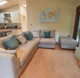 A living room with a gray sectional sofa cushions a colorful rug and a kitchen area at Beck of Beyond in Ambleside