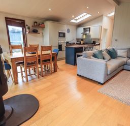 A living room with a grey sectional sofa and kitchen with wooden dining table and chairs at Beck of Beyond in Ambleside