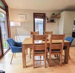 A dining area with a wooden table and chairs next to large windows at Beck of Beyond in Ambleside