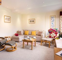 A living room with a beige sofa yellow and patterned cushions a wooden coffee table and armchairs at Lingmoor View in Chapel Stile