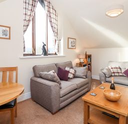 A living room with two sofas cushions a wooden coffee table and a round wooden dining table with chairs at Squirrel Bank in Ambleside