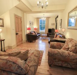 A living room with floral armchairs leather sofas wooden floor and a wood stove at Fairy Glen in Grasmere near Ambleside