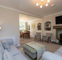 A living room with sofas armchairs a wood burner tv and a dining area with a table and chairs at Crozier Cottage in Grasmere