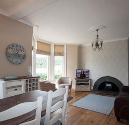 A living room with a dining table chairs a television fireplace and armchairs at Waterside Ambleside