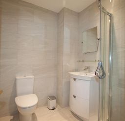 A bathroom with a toilet sink with mirror and glass shower enclosure at Waterside in Ambleside