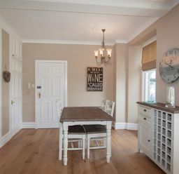 A dining room with a wooden table and chairs a chandelier a wall clock and a cupboard at Waterside in Ambleside