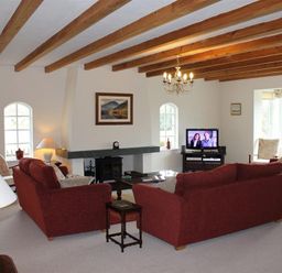A living room with wooden ceiling beams red sofas a fireplace and a television at Bandol in Braithwaite