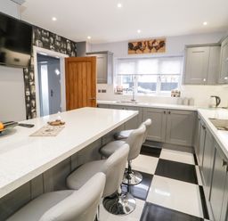A kitchen with a countertop island and gray cabinets at Meadow View in Tyn-y-Gongl near Benllech