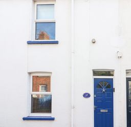 Exterior of a white building with two blue doors and two windows at South Harbour Cottage in Weymouth
