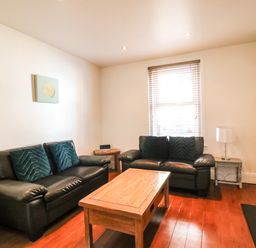 A living room with two black sofas a wooden coffee table and a window at South Harbour Cottage in Weymouth
