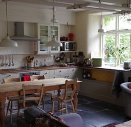 A kitchen with wooden table and chairs stove oven and hanging lights at Thomas Cottage in Hartsop