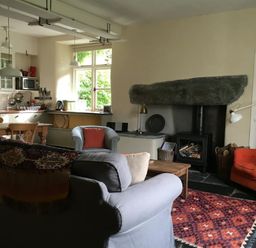 A living room with seating and a fireplace near a kitchen at Thomas Cottage in Hartsop
