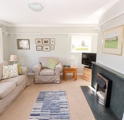 A living room with a sofa armchair rug fireplace and television at Brimbles in Keswick