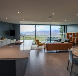 An open plan kitchen and living area with a kitchen island a sofa and a large window with mountain views at Gillside in Millbeck