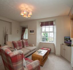 A living room with a sofa armchair coffee table and television at Swallow's Nest in Windermere