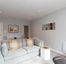 A sitting room with a grey sofa with yellow plaid cushions and a small white side table at Silver Howe in Grasmere