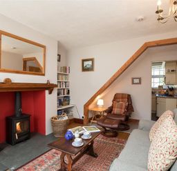 A living room with a fireplace a wood stove a gray sofa and a brown recliner at Briardale Cottage in Ambleside