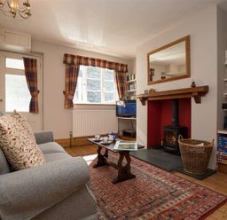 A living room with a gray sofa a wooden coffee table a fireplace and bookshelves at Briardale Cottage Ambleside