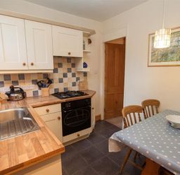 A kitchen with wooden countertops a sink a gas stove and a dining table with polka dot tablecloth at Briardale Cottage in Ambleside