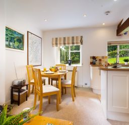 A dining area with wooden table and chairs next to a kitchen with countertop and sink at The Hayloft in Ambleside