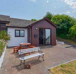 A patio area with a picnic table and a bench outside a single-story building at SoundView in Down Thomas