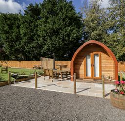 A wooden pod with a patio and outdoor furniture surrounded by a fenced garden at Halmore Pod in Halmore near Berkeley