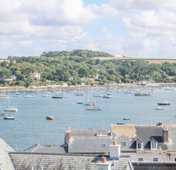 A harbor with many sailboats on the water and trees on a hill in the background at Through The Porthole in Falmouth