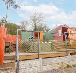 An outdoor area with a wooden deck and a green structure at The Rhiw in Llanfair Caereinion
