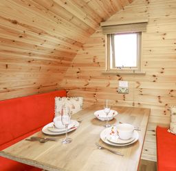 A dining area with a wooden table red bench seats and a window at Oak View in Llandovery