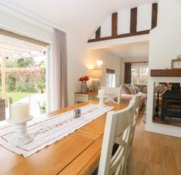 A dining table with candles and a table runner next to a fireplace and a living area at The Lodge in Wroxham