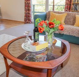 A living room with a coffee table holding flowers wine and glasses and a sofa with cushions at Goldcrest in Newport Pembrokeshire