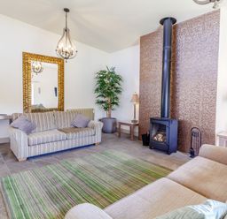 A living room with two sofas a green striped rug a fireplace and a large mirror at The Croft in Leigh Sinton