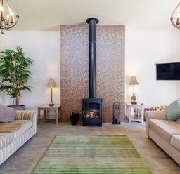 A living room with two sofas a wood stove fireplace green area rug and wall mounted television at The Croft in Leigh Sinton