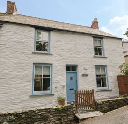 A white stone cottage with blue window frames and door a small wooden gate and potted plants at Fairfield Cottage Boscastle