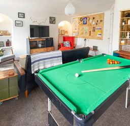 A living room with a pool table a sofa a red chair a television and shelves at 1 Pringles Yard in Alnwick