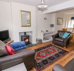 A living room with leather sofas a stove television and a dining table at Victoria Cottage in Chipping Norton