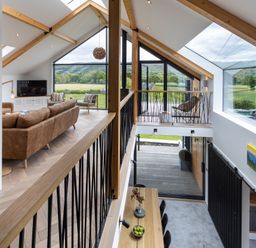 An upper living area with brown sofas and armchairs and a lower dining area with a wooden table and chairs at Gatesgarth in Coniston